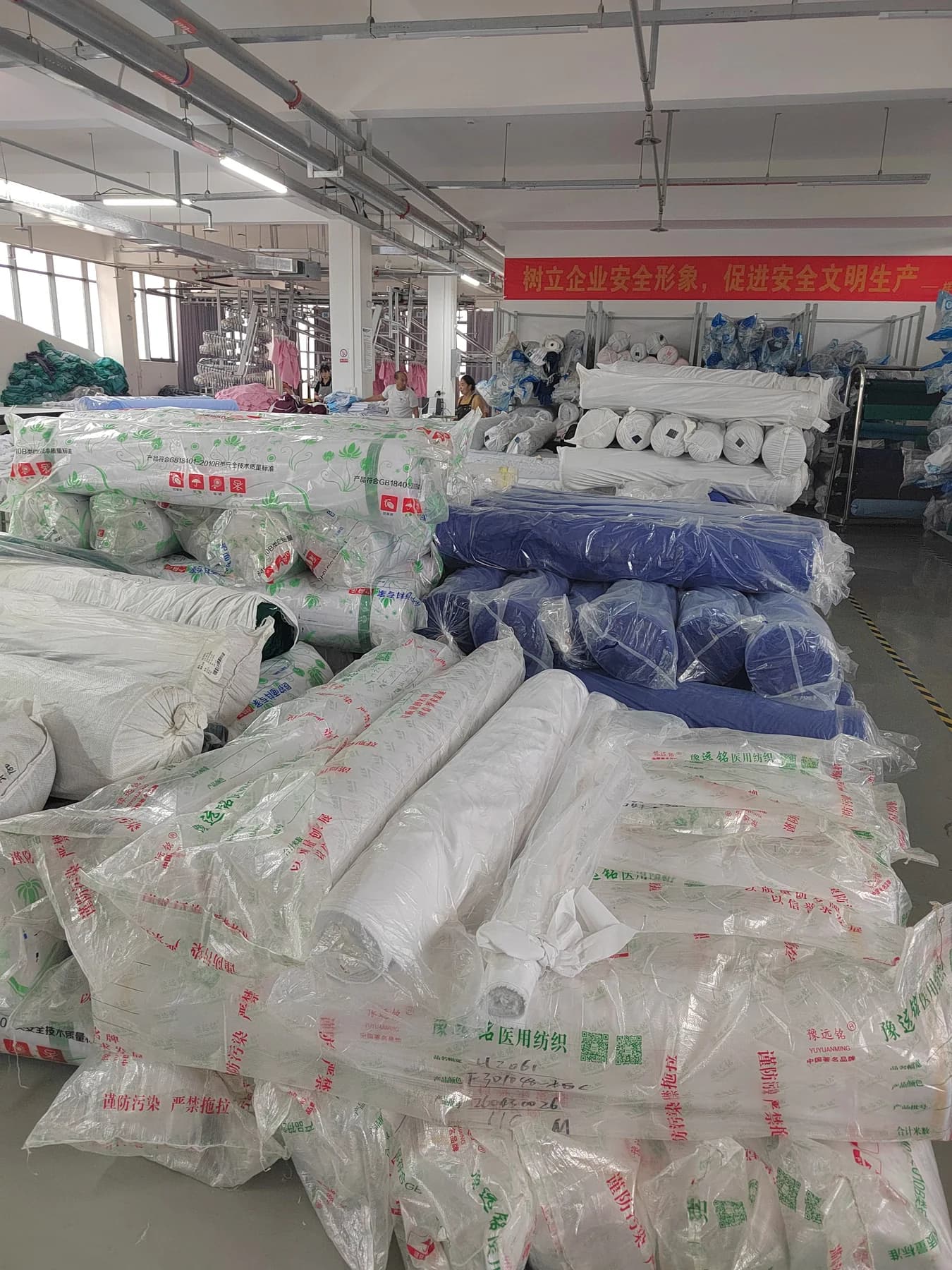 Wrapped rolls of white and blue fabric stored in the medical uniform workshop