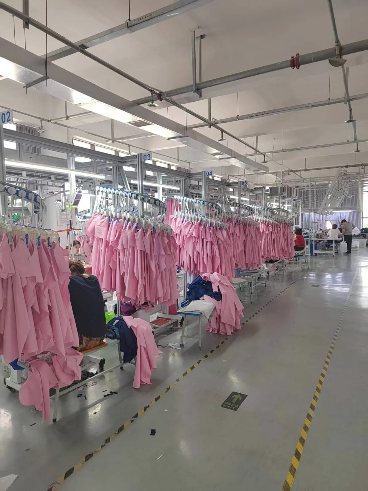 Pink uniform garments hanging along the medical uniform workshop production line